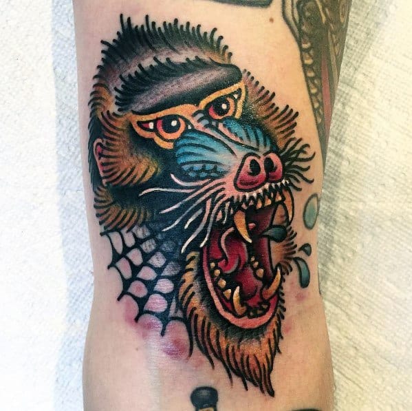 Neo-traditional baboon tattoo with bold outlines, vivid colors, and fierce expression, featuring scale details and water droplets for a dynamic design.
