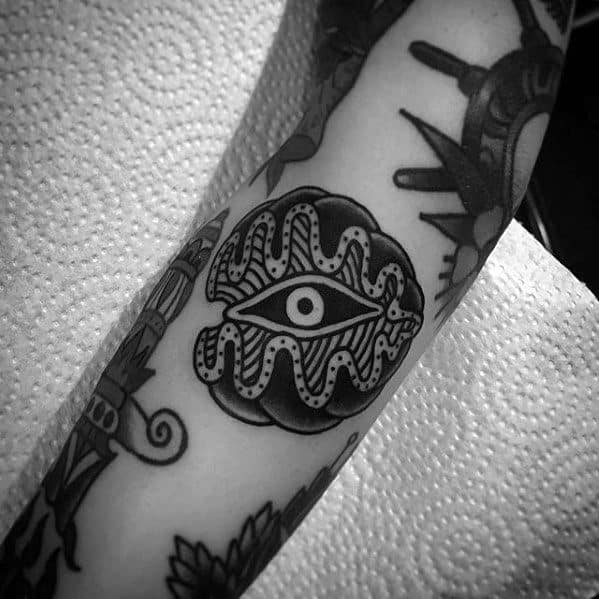 Bold blackwork clam tattoo featuring an all-seeing eye inside the shell, with dotted detailing and strong traditional-style outlines.