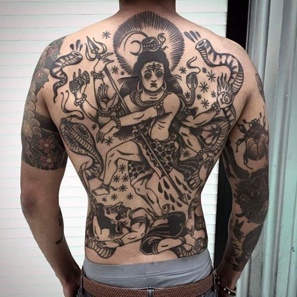 Bold full-back tattoo of Lord Shiva in a dynamic cosmic dance pose, surrounded by snakes, tridents, and celestial symbols in a traditional blackwork style.