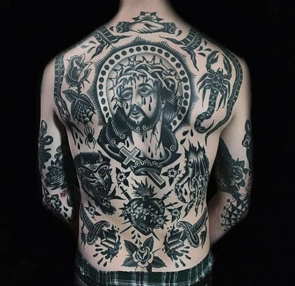 Person's back covered in black tattoos depicting various religious and decorative themes