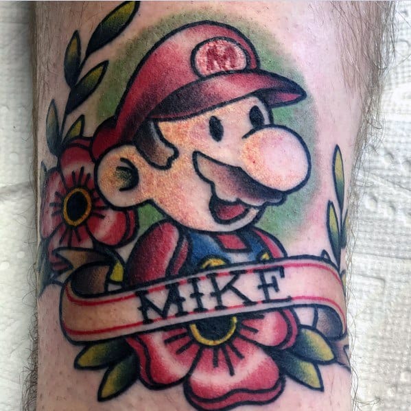 Traditional-style *Super Mario* tattoo featuring bold outlines, floral elements, and a banner with the name "Mike" for a classic and personalized design.