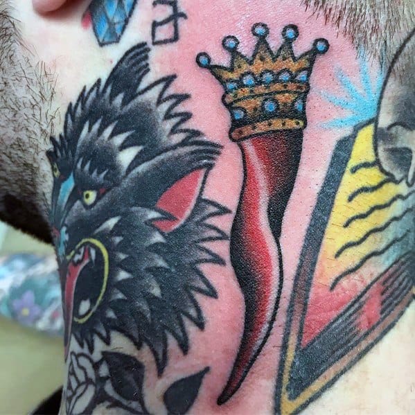 Bold Italian horn tattoo with a golden crown, symbolizing luck and protection, placed among other vibrant traditional designs.