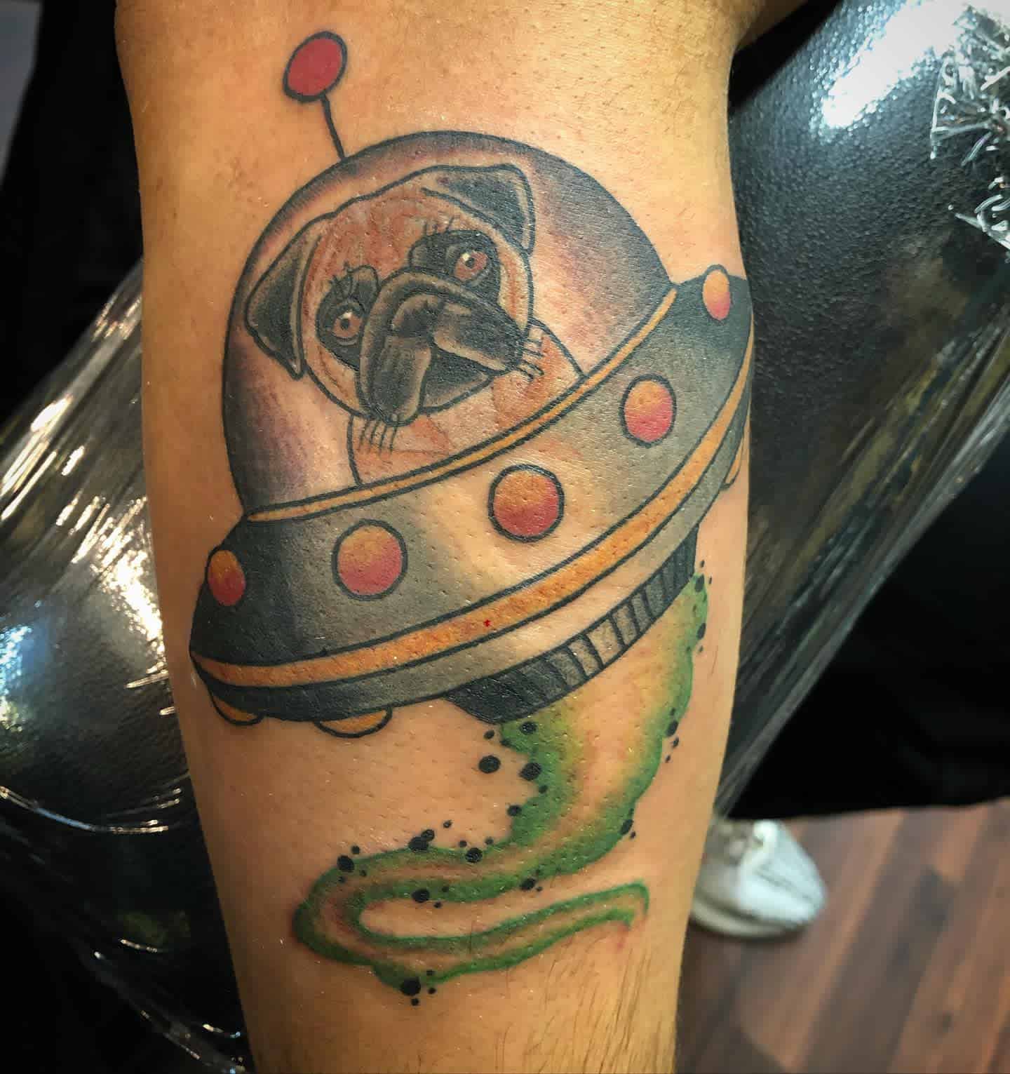 Tattoo of a pug in a UFO spaceship, with green smoke trailing below