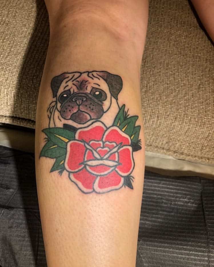 Tattoo of a pug's face above a red rose with green leaves 