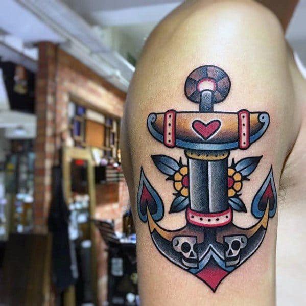 Colorful anchor tattoo adorned with flowers and skulls on upper arm