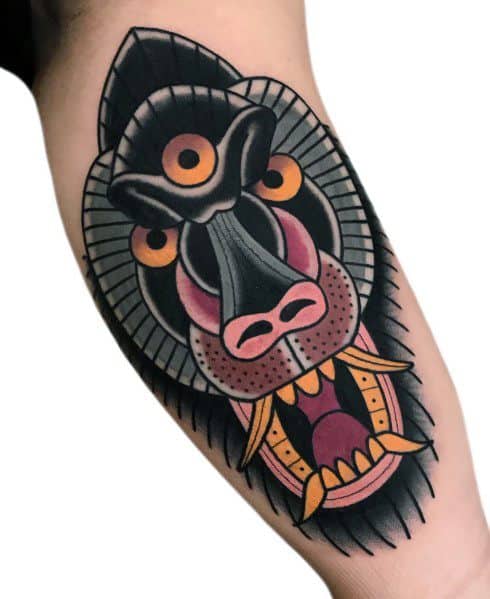 Traditional-style baboon tattoo with bold outlines, vivid colors, and a fierce open-mouthed expression, featuring geometric elements for a striking look.