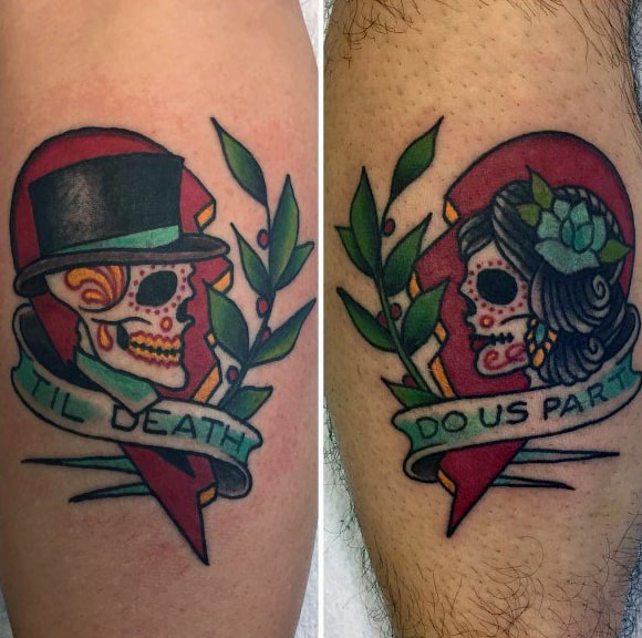 Matching tattoos of sugar skull bride and groom with a split heart and banner reading “’Til Death” and “Do Us Part,” symbolizing eternal love.