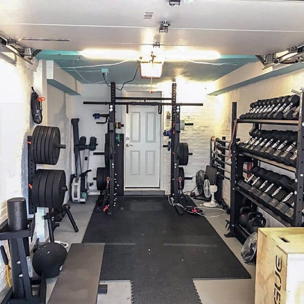 Compact garage gym with power rack, dumbbell racks, weight plates, and rubber flooring.