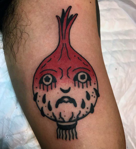 Bold neo-traditional tattoo of a crying anthropomorphic red onion with exaggerated facial features, dark outlines, and vibrant shading for a striking look.