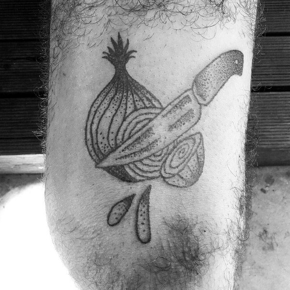Black ink tattoo of a sliced onion with a knife through it, featuring bold lines, dot shading, and dripping details for a traditional-style design.