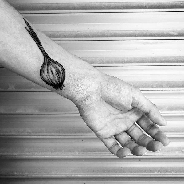 Minimalist black ink onion tattoo on the forearm, featuring fine line details, long sprouting leaves, and delicate shading for a sleek botanical look.