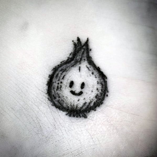 Small, sketch-style onion tattoo with a cute smiling face, featuring rough, hand-drawn lines and subtle shading for a playful, minimalist look.