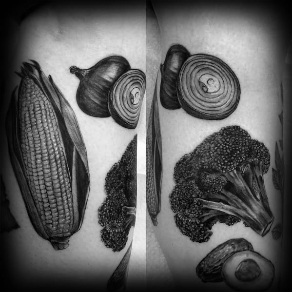 Realistic black and grey vegetable tattoo featuring onions, corn, broccoli, and an avocado, with intricate shading and fine details for a lifelike effect.