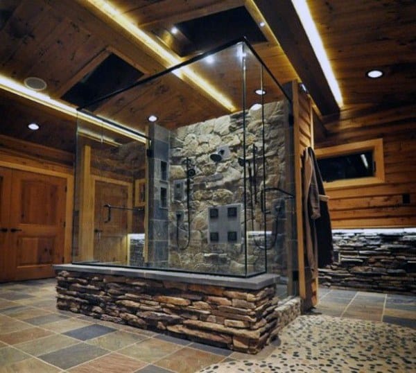 Rustic shower with stone walls and a glass enclosure in a wooden bathroom
