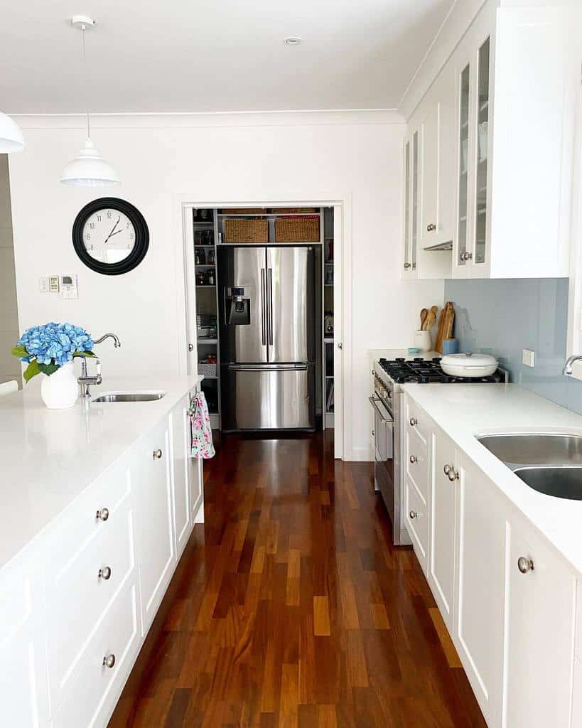 large galley kitchen white cabinets dual sinks wood flooring