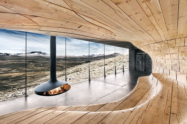 Floating fireplace in a wooden lounge with panoramic mountain views.