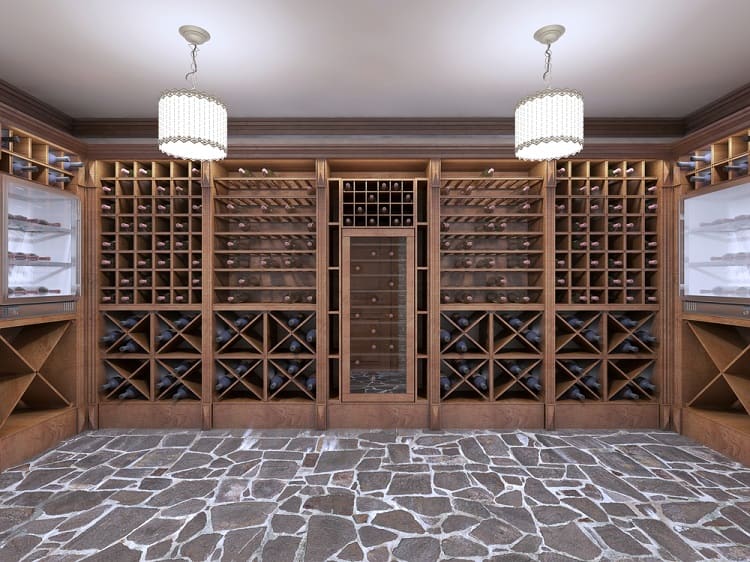 Spacious wine cellar with wooden racks and stone flooring, lit by elegant hanging lights.