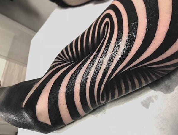 Blackwork optical illusion tattoo with bold, swirling lines creating a dynamic, hypnotic effect across the leg.