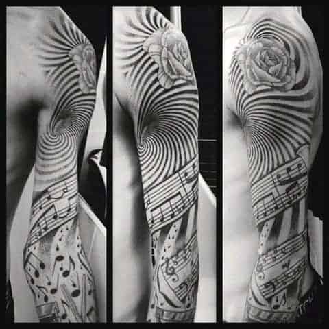 Black and white full sleeve tattoo on arm with rose, spiral, and musical notes