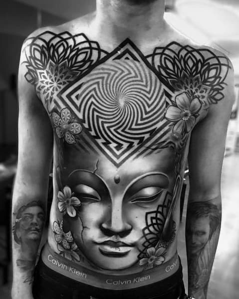 Black and grey full-torso tattoo featuring a serene Buddha face, intricate geometric patterns, floral elements, and a hypnotic square design.