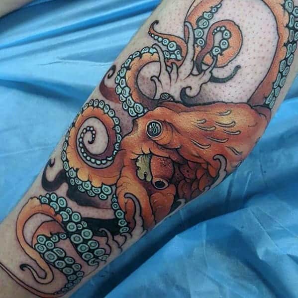 An orange Japanese octopus tattoo on the leg, showcasing vivid details with swirling tentacles and suction cups, complemented by a bold, colorful design for a dynamic and aquatic-themed artwork