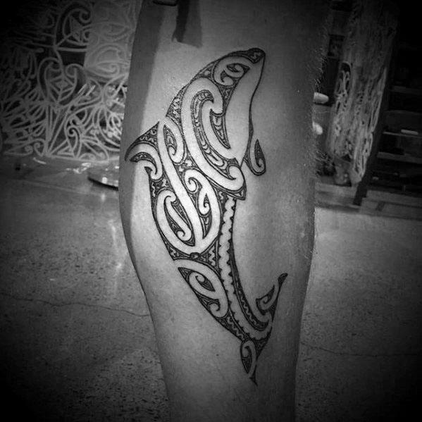 Tribal-inspired orca tattoo on the calf, featuring elegant, swirling patterns and bold black lines, capturing the whale's shape with intricate detailing.