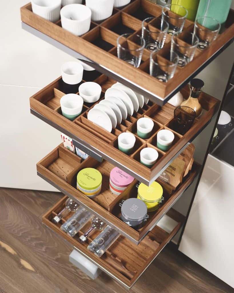 Wooden pull-out kitchen organizer with compartments for cups plates jars and bottles.