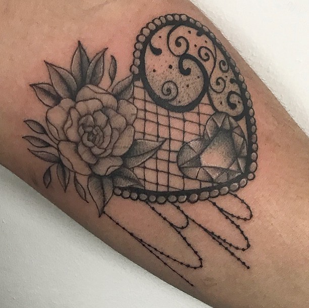 Elegant heart-shaped lace tattoo with a rose, filigree details, a gemstone, and delicate beaded chain accents."