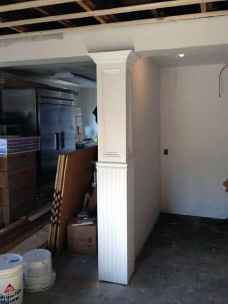 Unfinished basement with ornate millwork pole and exposed ceiling beams.