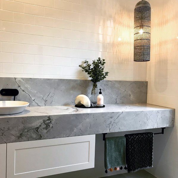 Modern bathroom with marble vanity, Moroccan wrought iron pendant light, and white subway tiles.
