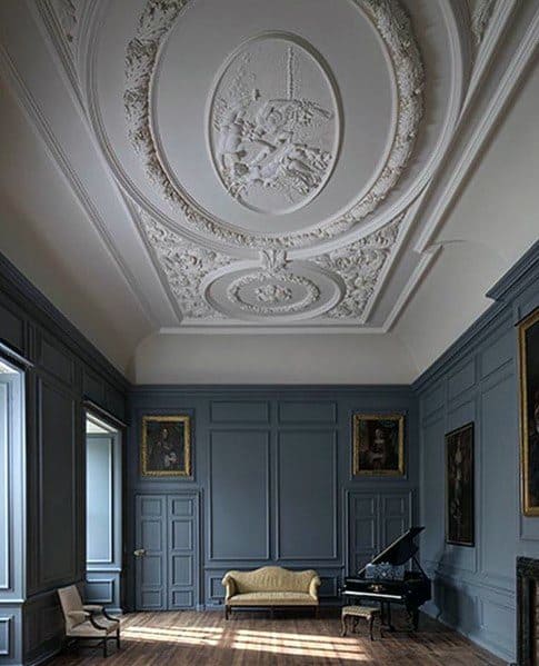 Elegant room with intricate ornate ceiling patterns, crown molding, and rich blue walls, featuring a vintage sofa and a grand piano