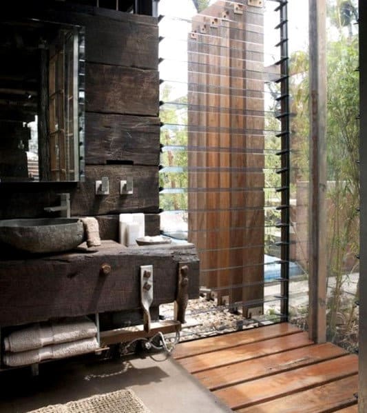 Rustic bathroom with wooden elements, stone sink, and slatted window with outdoor view