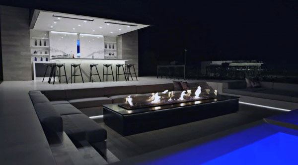 Stylish outdoor bistro bar with island seating, fire pit, and cozy lounge area at night.