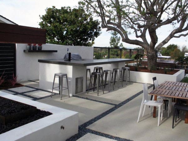 Outdoor bistro bar with concrete countertops, metal bar stools, and modern patio dining area.