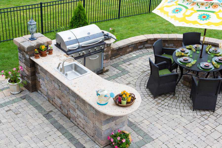 Chic outdoor kitchen with a built-in BBQ, sink, and a rounded stone bar and dining space.
