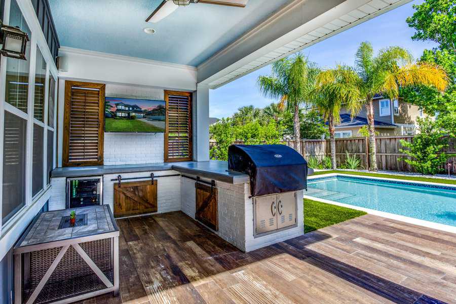 Stylish backyard with a pool, outdoor kitchen, BBQ grill, and rustic wood accents.