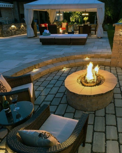 Cozy patio with a fire pit, wicker chairs, and a gazebo with seating in the background