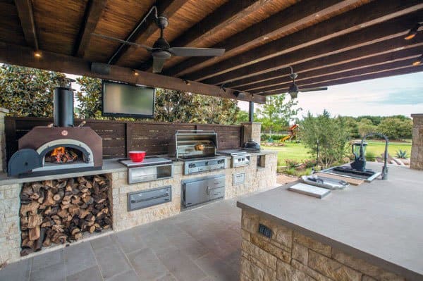 Outdoor pavilion with a built-in pizza oven, grill, spacious countertop, and wood storage, ideal for outdoor cooking.