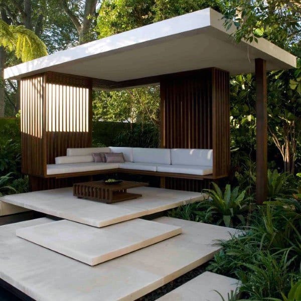 Sleek modern flat-top pavilion with floating steps, built-in seating, and elegant wooden accents in a lush garden.