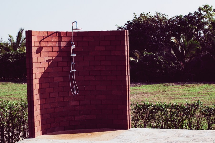 Brick outdoor shower with a curved wall design, offering privacy while blending with natural surroundings.