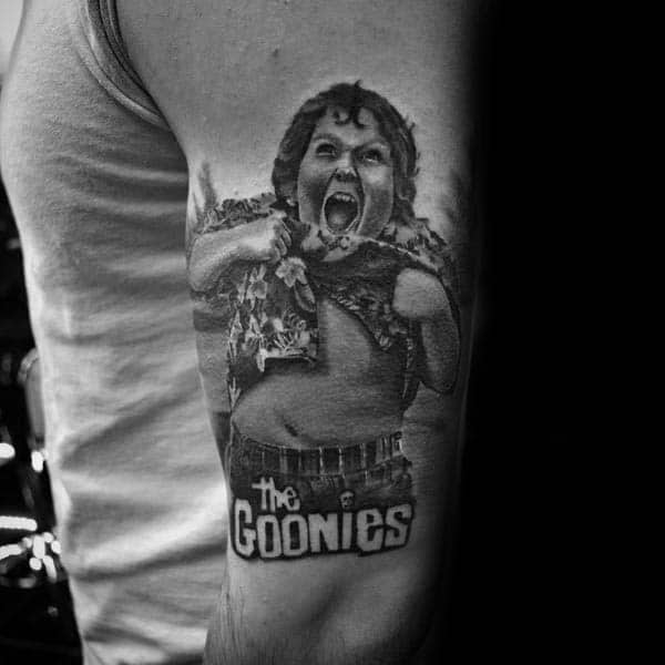 Black and gray realistic tattoo of Chunk from The Goonies performing the Truffle Shuffle, with "The Goonies" text below.