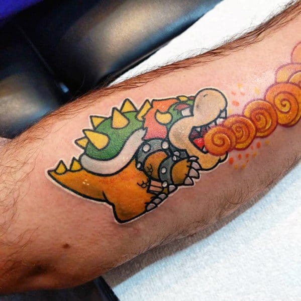 Cartoon-style Bowser tattoo on a man's leg featuring bold outlines, vibrant colors, and dynamic fire-breathing details in a playful Mario-inspired design.