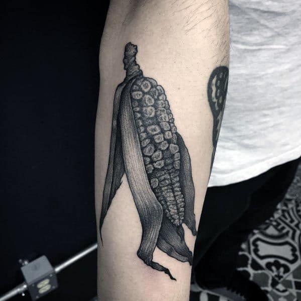 Black and gray tattoo of a detailed corn cob with husks, featuring intricate shading and a realistic texture for a bold design.