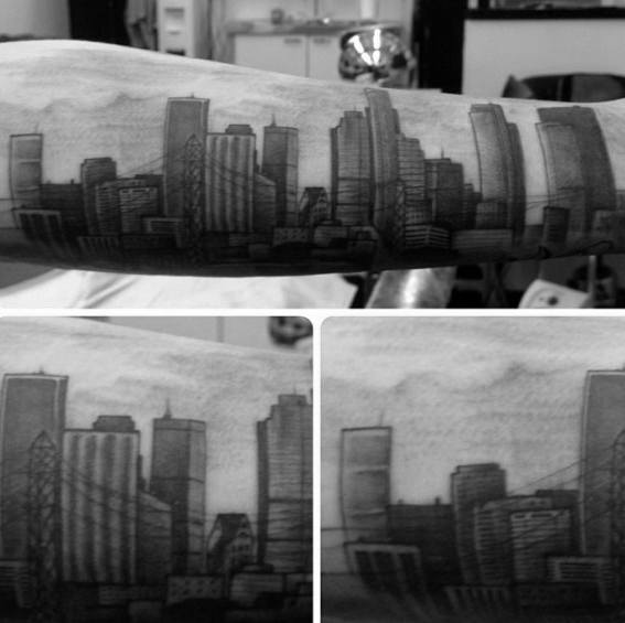 Realistic black and gray forearm tattoo of the Los Angeles skyline with detailed skyscrapers and soft cloud shading.