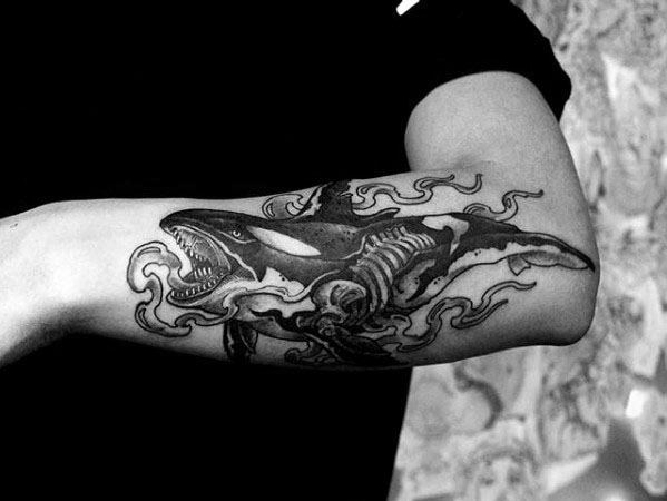 Black and gray orca tattoo on the forearm, showcasing the whale with a skeleton and dynamic waves, creating a dramatic and powerful design.