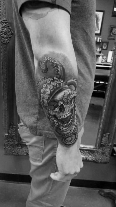 Skull entwined with octopus tentacles, with detailed shading and contrasts, creating a bold and dramatic black-and-grey design on the forearm.