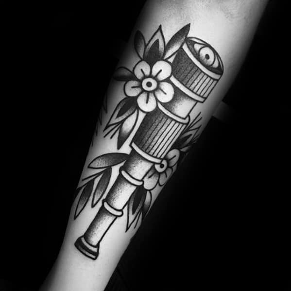 Tattoo of a telescope entwined with flowers and leaves in black and gray shading