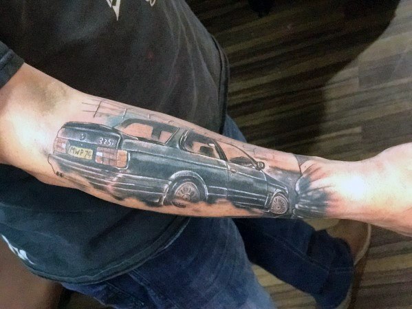 Realistic BMW 325i touring tattoo on forearm, featuring dynamic motion effects and detailed shading for a bold automotive design.