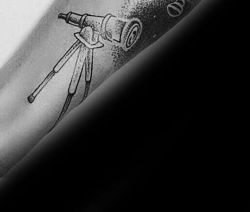 Telescope tattoo on a tripod against a dark backdrop
