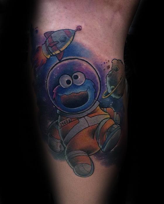 Cookie Monster astronaut tattoo floating in a vibrant galaxy, wearing an orange space suit with a rocket and cookie-shaped planet nearby.